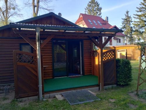 eine Hütte mit Markise und einer grünen Veranda in der Unterkunft Ferienhaus am Müritz Nationalpark in Waren (Müritz)