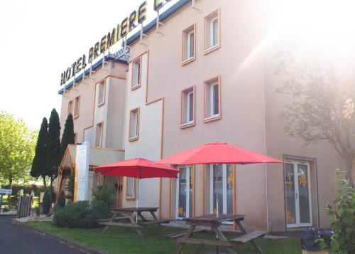 two picnic tables with umbrellas in front of a building at Premiere Classe Niort Est - Chauray in Niort