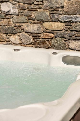 a bath tub filled with water next to a stone wall at BELLA VITA Residence in Gravedona