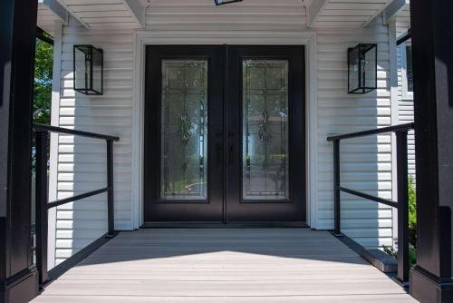 a black door with glass windows on a white house at Coastal Retreat: Waterfront, Deck, Awesome Views in Wading River