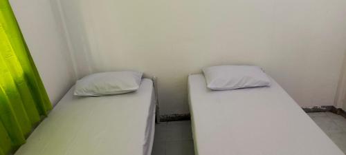 two beds in a corner of a room at Penginapan Cendrawasih in Sorong