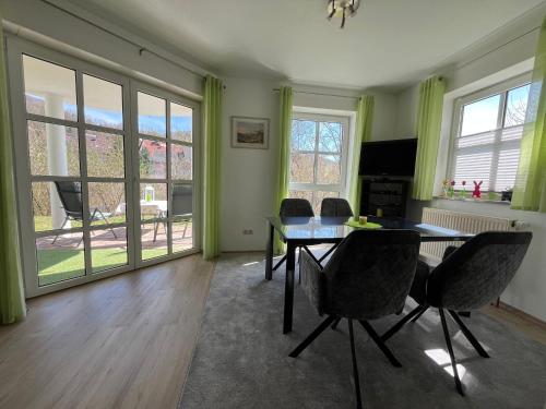 a dining room with a table and chairs and windows at Ferienwohnung Sonnengarten in Heiligenstadt