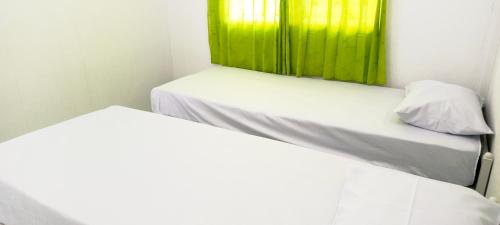 two beds in a room with a green window at Penginapan Cendrawasih in Sorong