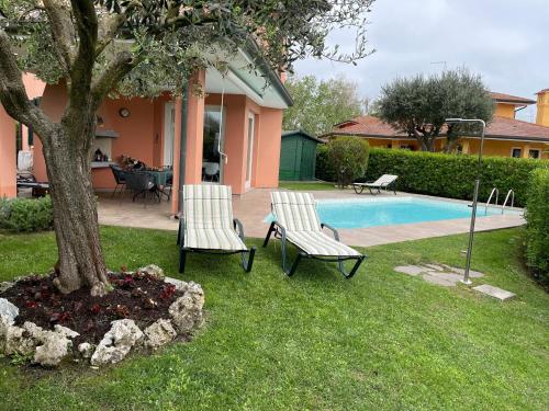 two chairs and a tree next to a swimming pool at Allegra in Caleri