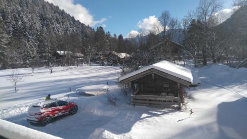 a car parked in the snow next to a cabin at Haus Bamberger in Fischbachau
