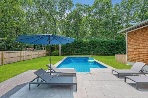 a pool with two lounge chairs and an umbrella at East Hampton Retreat: Heated Pool, BBQ,Home Office in East Hampton