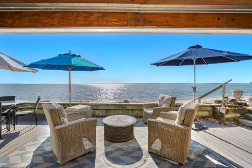 een patio met stoelen en parasols en uitzicht op de oceaan bij Bahia Mar: Beach House, North Fork in Laurel