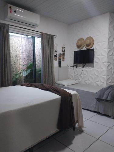 a bedroom with two beds and a tv and a window at Casa da isy hospedagem in Natal