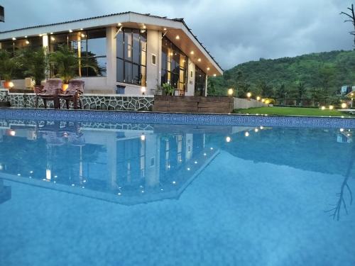 a house with a swimming pool in front of a house at HillRock Resort & Villas, Neral-Karjat in Karjat