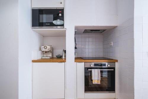 a small kitchen with a stove and a microwave at Dom Vasco 30 - Charm flat with garden by Belém in Lisbon