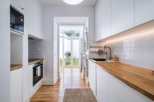 a kitchen with white cabinets and a wooden counter top at Dom Vasco 30 - Charm flat with garden by Belém in Lisbon