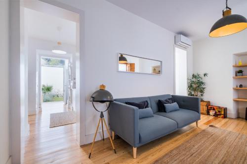 a living room with a blue couch and wooden floors at Dom Vasco 30 - Charm flat with garden by Belém in Lisbon