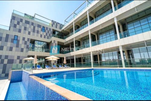 a swimming pool in front of a building at 2 Br Luxury duplex Canal View, 5 min to AUH Airport, Yas island , Raha mall in Abu Dhabi