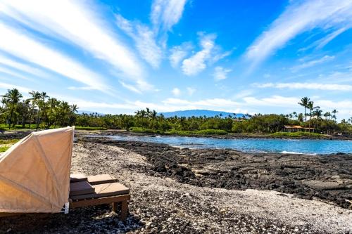 a chair and a tent on a beach next to a river at Mauna Lani Terrace D203 in Waikoloa