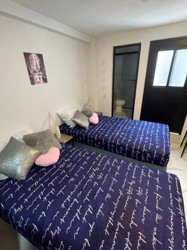 two beds sitting next to each other in a bedroom at Pinar de la Calma, mini casa totalmente renovada estilo Loft Renovada muy bien ubicada dentro de la ciudad sin salir al periferico a solo 5 minutos del Parque Industrial Tecnologico II Sur de la Ciudad ITESO TecMilenio UVM in Guadalajara