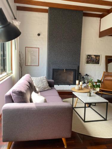 a living room with a purple couch and a fireplace at Vistamar Duplex in Lima