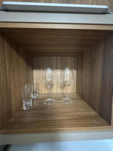 three wine glasses sitting on a wooden shelf at Departamento céntrico Félix de Azara in Puerto Iguazú
