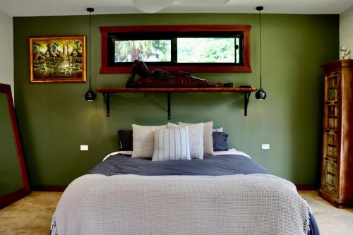 a bedroom with a bed with green walls and a window at Alam Kesehatan Wellness retreat in Nimbin