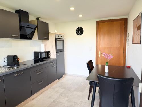 a kitchen with black cabinets and a table with chairs at Gaucho Home in Fußach