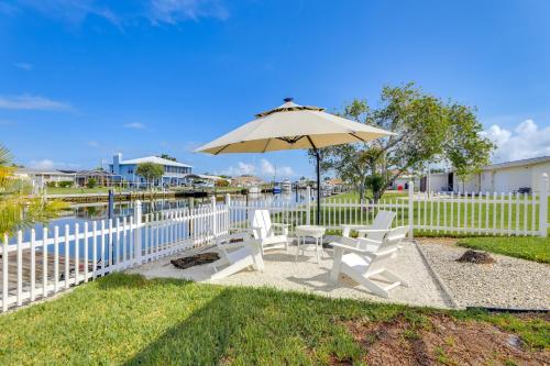a white fence with two chairs and an umbrella at Canal-Front Haven Pool, Dock and Lanai in Palmetto in Palmetto