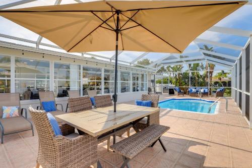 a patio with a wooden table and chairs and an umbrella at Canal-Front Haven Pool, Dock and Lanai in Palmetto in Palmetto