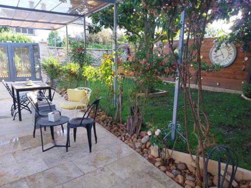 eine Terrasse mit einem Tisch, Stühlen und einer Uhr in der Unterkunft Maison en rez-de chaussée près du centre ville d'Arles in Arles