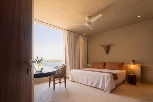 a bedroom with a bed and a desk and a window at Punta Majahua by PRC Hospitality in La Majahua