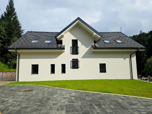 una casa blanca con techo negro en Apartmaji Vouk - sodobni apartmaji v objemu narave - Lukanja - Rogla - Primerno za pare in družine - Sprostitev in aktivno preživljanje prostega časa, en Oplotnica