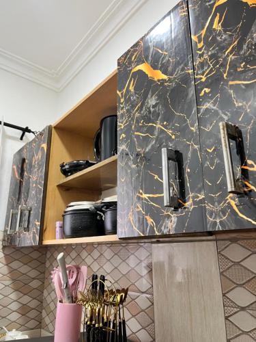 By the Coastals في مومباسا: مطبخ بخزائن رخامية باللونين الأسود والذهبي