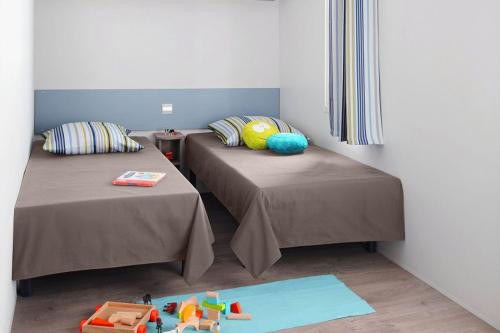 a bedroom with two beds and a toy truck on the floor at Camping Rouffignac-St-Cernin in Ladeymarie