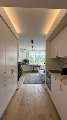 een keuken met witte kasten en een woonkamer bij Algirdo Sunlight Studio in Vilnius
