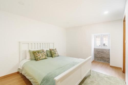 a white bedroom with a white bed and a window at Casa de Lamalonga T2 in Campos