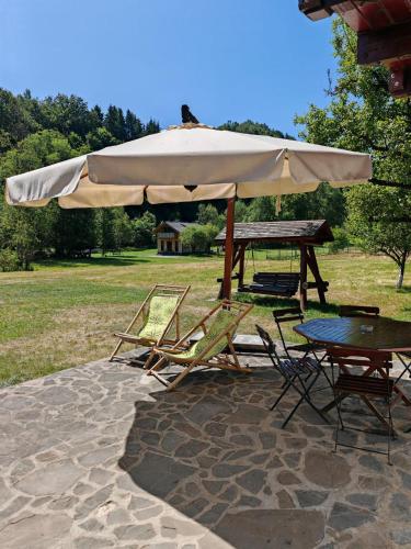 a table and chairs under a large umbrella at Căsuța dintre Meri in Moieciu de Jos
