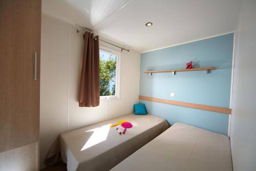 une petite pièce avec un lit et une fenêtre dans l'établissement Camping Saint-Nazaire, à Saint-Nazaire