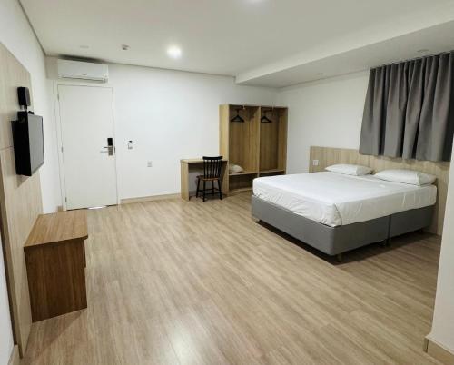 a bedroom with a bed and a desk and a television at Riellis Center Hotel in Botucatu