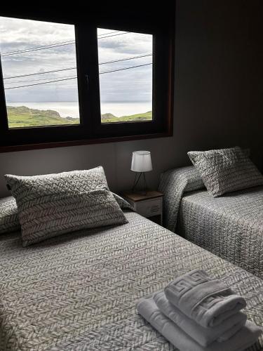 a bedroom with two beds and a window at Apartamentos El Prau in Ubiarco