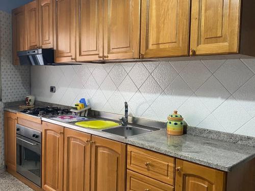 a kitchen with a sink and a stove and wooden cabinets at Appartamento Nonna Ida in Montesarchio