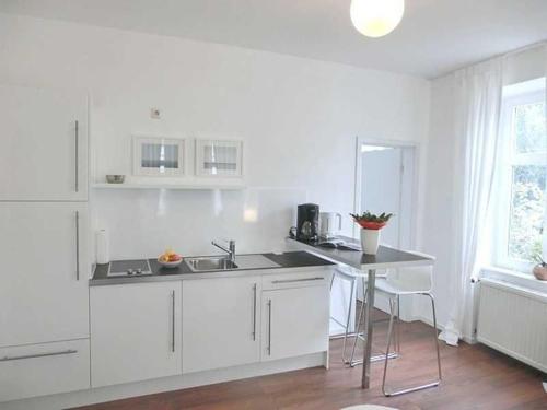 a white kitchen with a sink and a table at Villa Melanie in Sassnitz