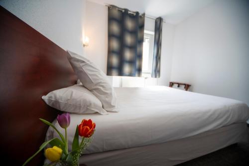 a bedroom with a bed with white sheets and flowers at Logis Hôtel & Restaurant Au Lion d'Or in Burnhaupt-le-Haut