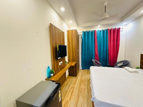 a bedroom with a bed and a tv and a window at Welcome buddy studio apartment in Greater Noida