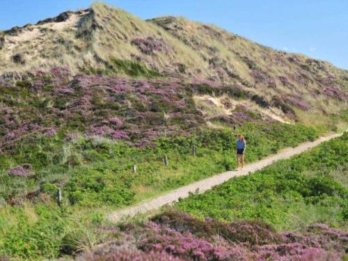 a woman walking down a dirt path on a hill at Enenhoog Flugente von Appartements & Mehr in Kampen