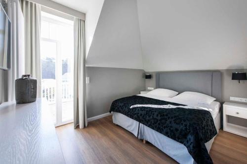 Un dormitorio con una cama y una ventana grande. en "Villa Minerva" Ferienwohnung 09, en Kühlungsborn