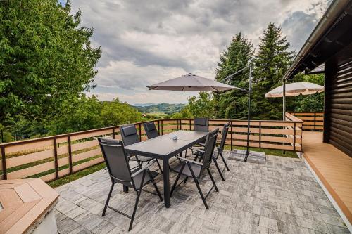 a table with chairs and an umbrella on a deck at Log Cabin Vista View with Seasonal Hot Tub in Bizeljsko