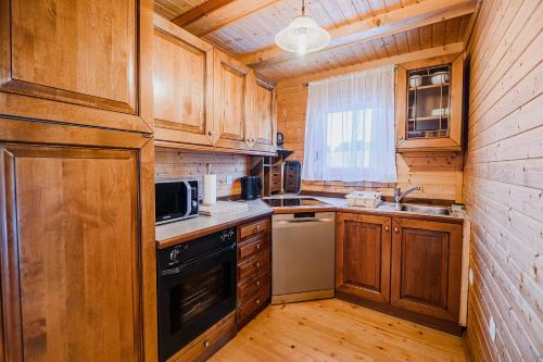 a kitchen with wooden cabinets and a stove top oven at Log Cabin Vista View with Seasonal Hot Tub in Bizeljsko