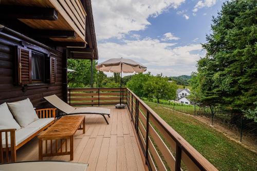 a wooden deck with a couch and an umbrella at Log Cabin Vista View with Seasonal Hot Tub in Bizeljsko