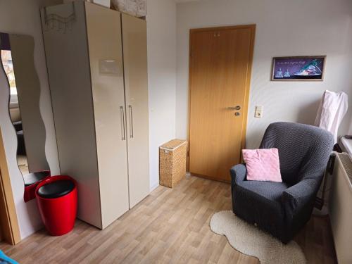 a living room with a chair and a cabinet at Ferienwohnung Martina in Hasselfelde