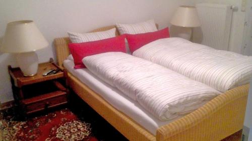 a bed with white and red pillows and two lamps at Ferienhaus "Buchholz" in Buchholz