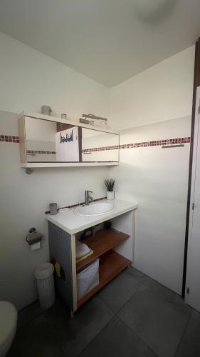 a white bathroom with a sink and a shelf at RDC Villa la mahaudière vue mer à 300m de la plage de Grande Anse in Deshaies