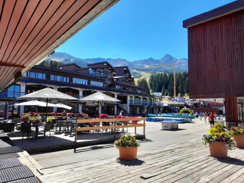 un complexe avec des tables, des chaises et des parasols dans l'établissement Résidence Bequi Rouge - 2 pièces 5 personnes MAE-8314, à Arc 1800