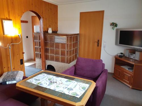 a living room with a purple couch and a tv at Nelius - Ferienhaus 1 in Stiege
